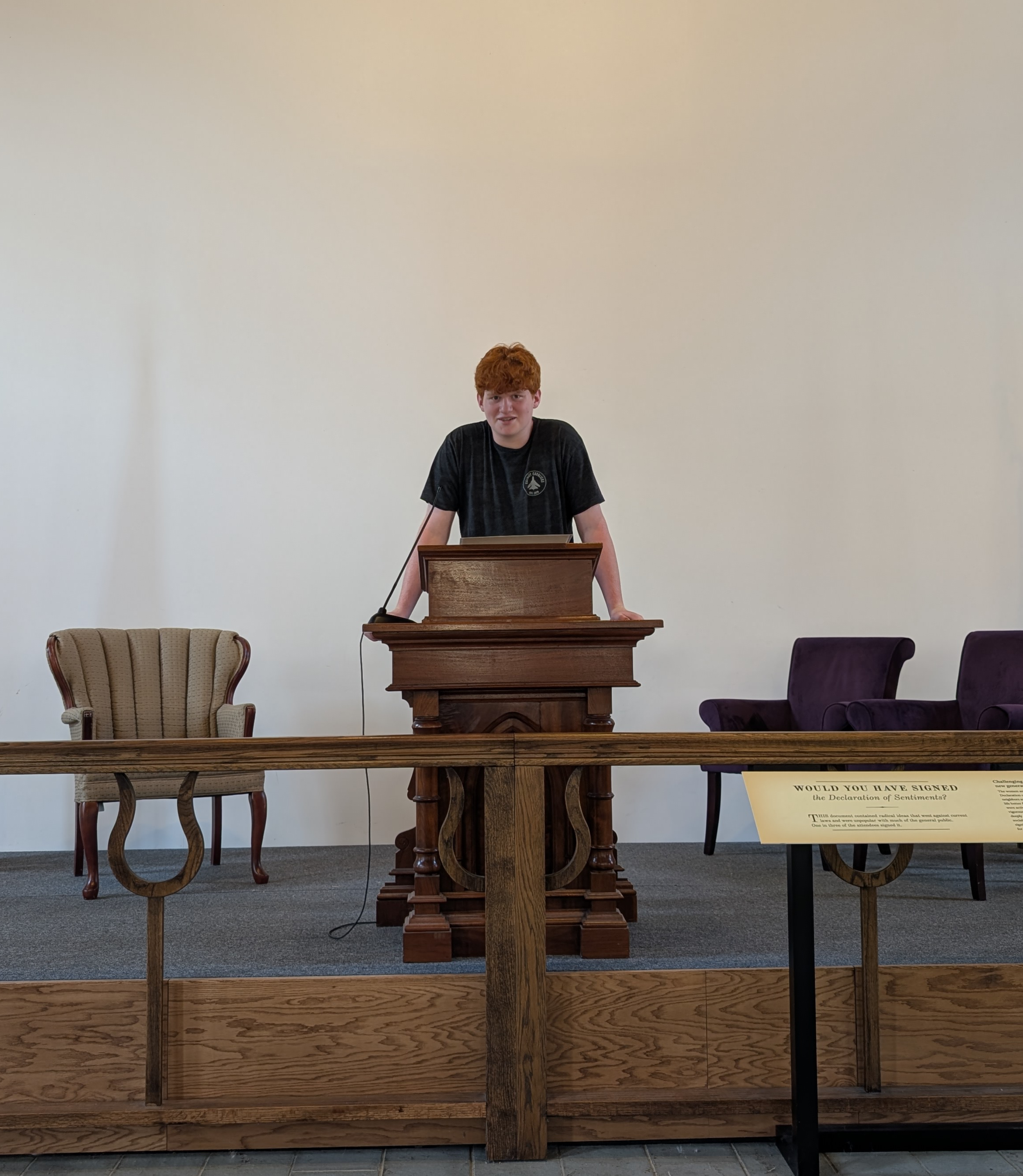 Interactive exhibit at the Women’s Rights National Historical Park depicting the 1873 trial of Susan B. Anthony. Remington McGill stands at a wooden courtroom-style podium, flanked by American and New York state flags. Behind a wooden barrier, a panel invites viewers to consider whether they would have served on the jury that found Anthony guilty for voting illegally in the 1872 election.